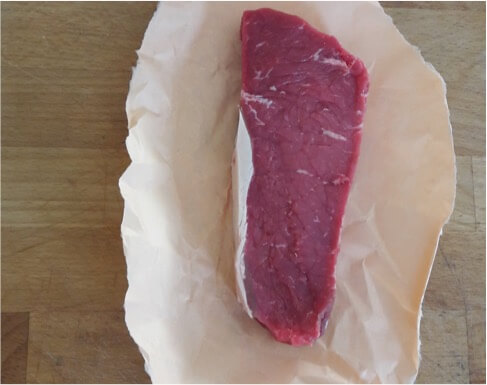 An image of a raw sirloin steak on butchers paper