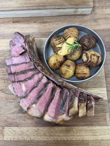Tomahawk with hassleback potatoes served